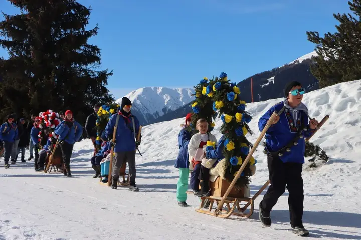 Kinder ziehen Rennbänna, im Hintergrund Berge