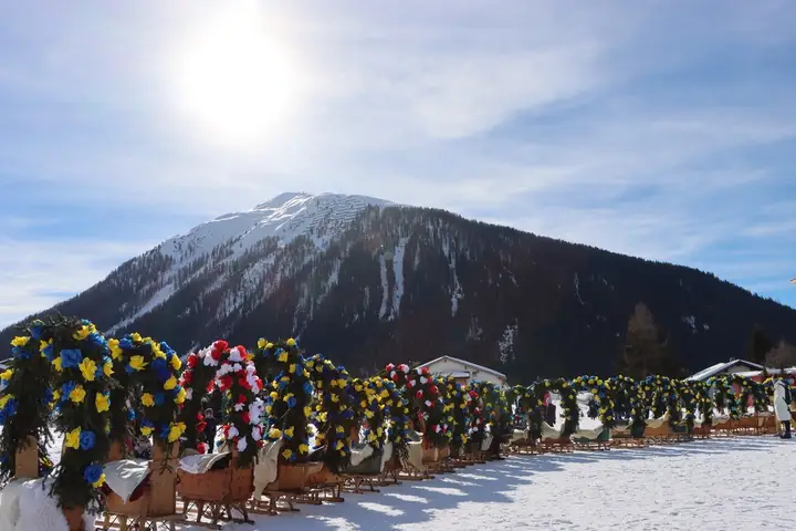 Eine Reihe geschmückter Rennbänna vor dem Berg im Gegenlicht