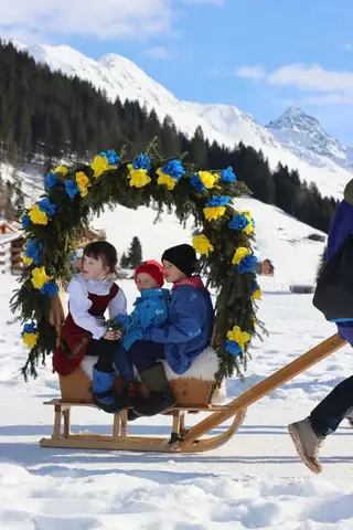 Zwei Kinder sitzen unter einem Rosenbogen auf der Rennbänna