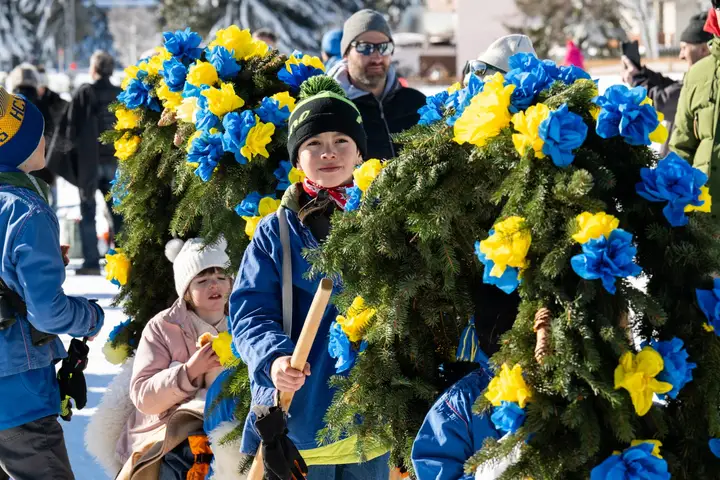 Kinder zwischen Rennbänna voller Papierrosen, dahinter Zuschauer
