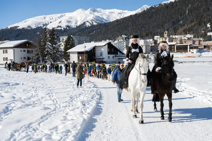 Zwei Füerriiter reiten dem Umzug voraus, dahinter das Dorf