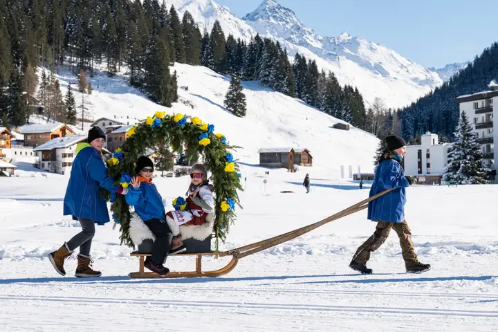 Eine Rennbänna mit blau-gelbem Rosenbogen, zwei Kinder sitzen darin