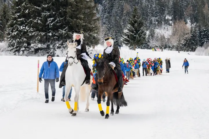 Zwei Füerriiter zu Pferd führen den Umzug über den verschneiten Weg an