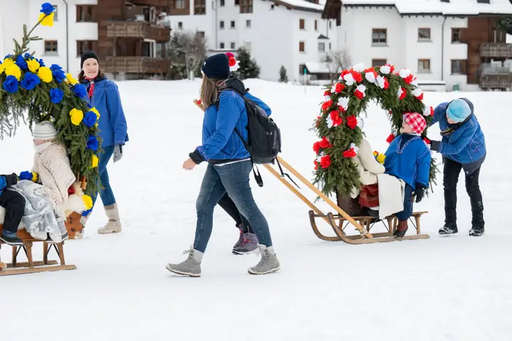 Eine Rennbänna mit rotem Rosenbogen wird über den Schnee gezogen