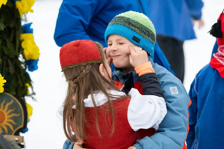 Zwei Kinder umarmen sich neben einer Rennbänna