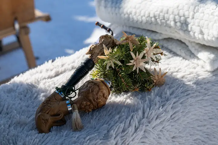 Eine geschnitzte Holzpfeife mit Tannenzweig und Edelweiss auf weissem Fell