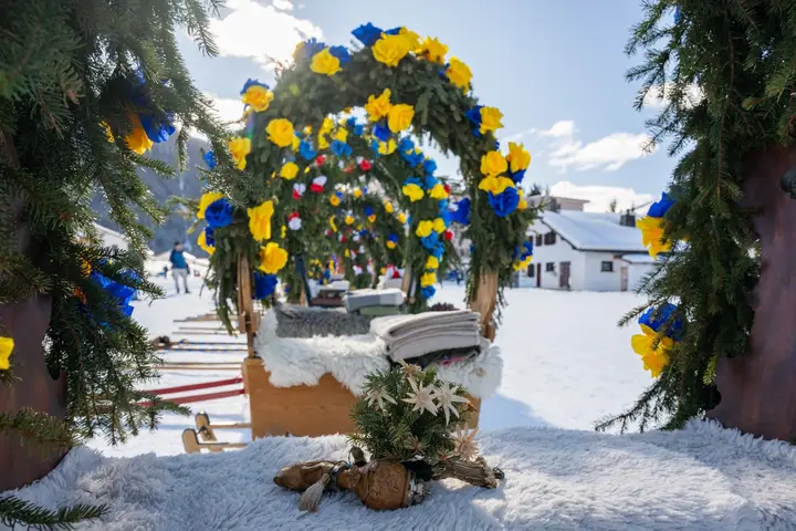 Ein Rosenbogen aus Tannenzweigen mit blauen und gelben Papierrosen