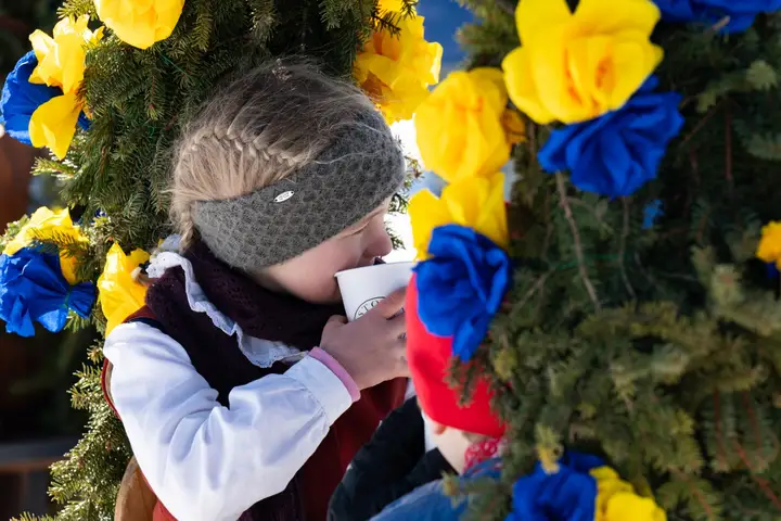 Ein Kind trinkt aus einem Becher, rundherum Papierrosen