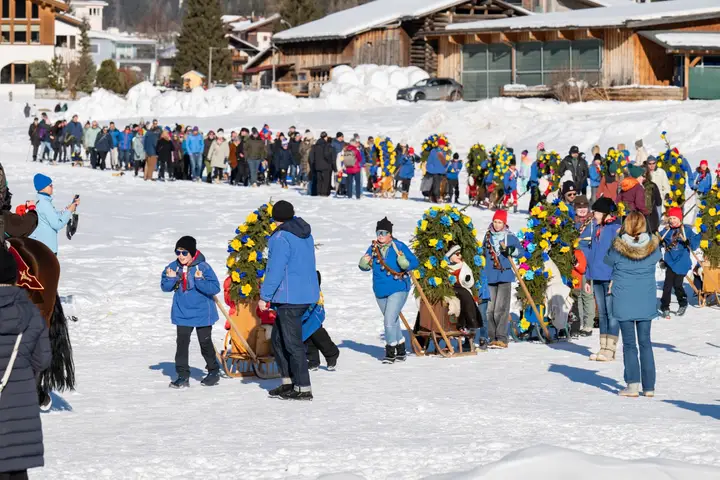 Zuschauer und Rennbänna in einer langen Reihe auf der Schneefläche