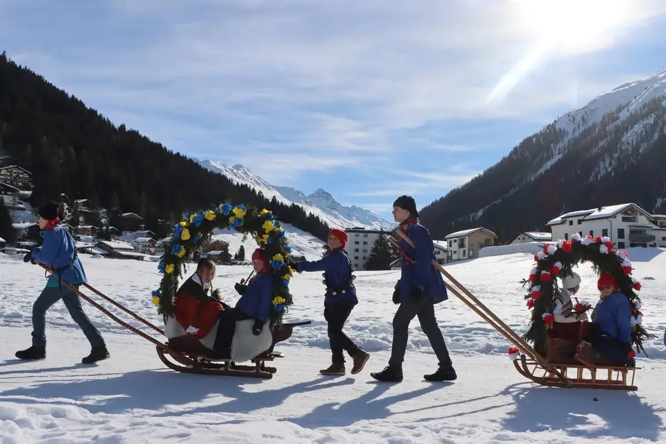 Zwei Rennbänna mit Rosenbögen ziehen über die Schneefläche